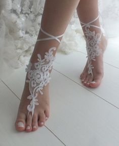 a woman's feet with white lace and flowers on the toe, barefoot sandals