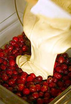 someone is pouring milk into a container full of strawberries and other fruit to be mixed together