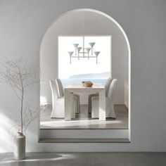 a white table and chairs in a room with an arch doorway leading into the dining area