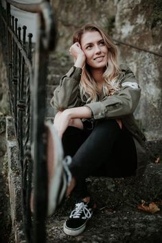 a woman sitting on the steps with her hand under her head and looking at the camera