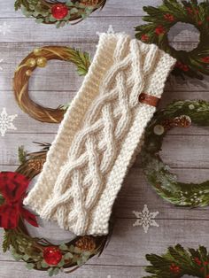 a white knitted mitt sitting on top of a wooden table next to wreaths