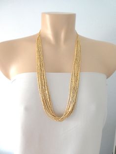 "Long necklaces for women boho layered. Measures 30\". It has 12 strands. ❤ PROCESSING AND SHIPPING Most orders are made and shipped out in one business day. Please check delivery timeframes for your location on the description below. ❤ CUSTOM ORDERS If you like this item in a different color, send me a message indicating: color, size and quantity needed. I will send you a link for a \"custom order\" and you'll be able to place the order there. If you like this item with some variations such as Gold Multi-strand Necklace With Gold Beads, Bohemian Gold Layered Necklace With Delicate Chain, Gold Long Beaded Necklace, Gold Multi-strand Chain Necklace, Gold Layered Bohemian Beaded Necklaces, Bohemian Gold Layered Beaded Necklaces, Bohemian Gold Long Necklace With Round Beads, Gold Multi-strand Beaded Necklaces With Tiny Beads, Gold Double Strand Beaded Necklaces With Tiny Beads