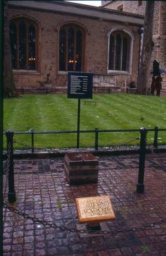 an old brick building with a plaque on the ground in front of it and a grassy yard behind it