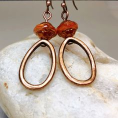 Hoop earrings in copper with stunning Saturn beads that are capped with a copper finish. These simple yet sophisticated dangle earrings are lightweight and comfortable for all day wear. Fabulous earrings in a trending color that can be worn with so many different outfits.   Hypoallergenic ear wires (nickel and lead free). Select ear wire style at checkout. Free gift packaging included. Earrings are carded and in an organza bag. Artisan glass beads produced in small quantities in the Czech Republ Handmade Copper Beaded Earrings, Bronze Teardrop Copper Earrings, Bronze Copper Teardrop Earrings, Bronze Copper Earrings With Dangling Beads, Orange Copper Dangle Earrings, Elegant Orange Copper Earrings, Brown Metal Hoop Earrings, Bronze Copper Hoop Earrings, Nickel-free Copper Teardrop Beaded Earrings