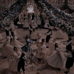 a group of people dressed in formal dress dancing on a floor with flowers all around