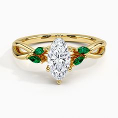 a yellow gold ring with an oval cut diamond and green leaves on the band, set against a white background