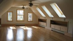 an empty room with wooden floors and two windows in the ceiling, some are open