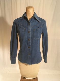 "vintage 1970s women's western denim shirt Brittania Sportswear cotton blue jean button up front 2 bust pockets long sleeve/button cuff yoke hem good vintage condition, light wear labeled size 5, very petite, see below measures, lying flat, shoulder-  13 1/2\" sleeve-20 1/2\" chest-16\" waist-14\" hem-16\" length from top at neck seam below collar-22\"" Fitted Vintage Button-up Denim Top, Classic Fitted Denim Top With Pockets, Vintage Relaxed Fit Shirt For Rodeo, Western Style Relaxed Fit Button-up Tops, Denim Blue Button-up Top For Rodeo, Fitted Medium Wash Denim Top With Button Closure, Denim Blue Long Sleeve Shirt For Rodeo, Long Sleeve Denim Blue Shirt For Rodeo, Non-stretch Long Sleeve Denim Tops