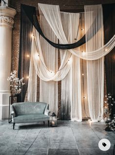 a room decorated with sheer curtains, candles and a blue chair in front of it