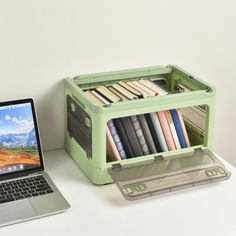 an open laptop computer sitting on top of a white desk next to a book case