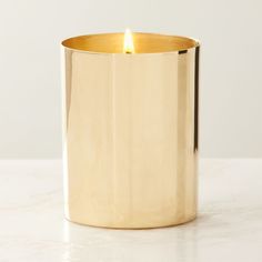 a gold colored candle holder on a white table with a light shining in the middle