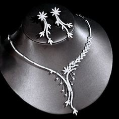 a necklace and earring set with flowers on a black plated surface in the dark