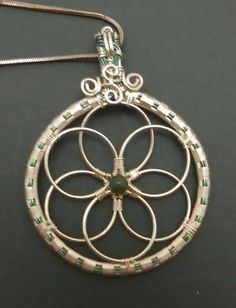 a silver pendant with green beads on it