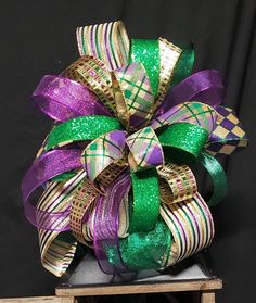 a purple and green bow on top of a black surface with gold foil strips around it