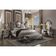 a bedroom with an ornate bed, mirrored dressers and chandelier on the wall