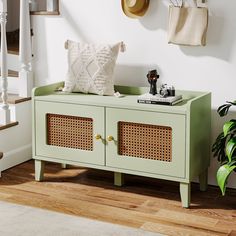 a green sideboard with wicker doors and two baskets on it in front of stairs