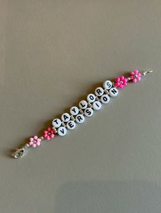 a keychain with the word love spelled in white letters and pink flowers on it