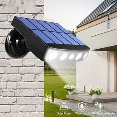 the solar powered security camera is on display in front of a white brick wall and green grass