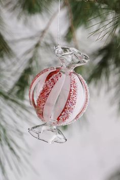 a glass ornament hanging from a christmas tree with red and white decorations on it