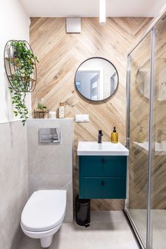 a white toilet sitting next to a bathroom sink under a mirror on a wooden wall