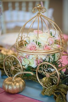 a gold birdcage filled with white and pink flowers sitting on top of a table