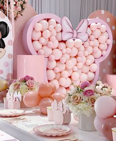 a table topped with lots of pink balloons and minnie mouse head shaped like a heart