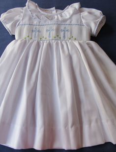 White dress hand smocked with delicate light blue crosses. Ties on the back Easter dress or christening dress is a beautiful dress delicately smocked with crosses. This dress can also be used not just for that special occasion or for any other special event, dedication or for older girls their First Holy Communion and portraits. Made to order. For customs made orders allow 2-3 weeks for delivery. White Smocked Dress, Craft Smock, Baptism Dress, Christening Dress, Easter Cross, Hand Smock, Most Beautiful Dresses, Blue Cross, Easter Dress