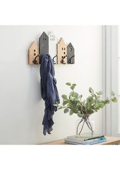 the coat rack is next to a potted plant and some books on a table