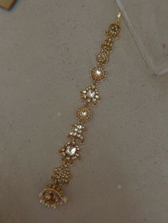 a gold bracelet with pearls and beads on the bottom is shown in close up view