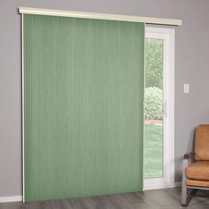 a living room with a chair and sliding glass door that has green blinds on it