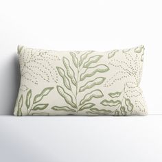 a white pillow with green leaves on it