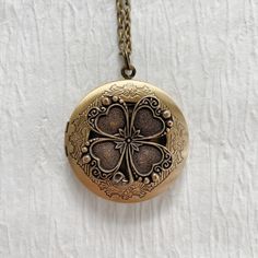 "Please note: If you need more than one, multiple quantities are available upon checkout. Timeless and classic, this gorgeous antiqued silver or gold clover locket will become a special addition to your jewelry collection. The locket is 32mm in diameter, silver or gold plated brass and opens for a secret place to keep pictures, messages, or whatever you like. The locket has an antique silver stainless steel rolo chain or antique gold solid brass chain with a lobster clasp. You may choose 18', 20 Antique Medallion Jewelry For Good Luck, Antique Engraved Jewelry For Good Luck, Antique Engraved Good Luck Necklace, Antique Engraved Necklace For Good Luck, Vintage Good Luck Locket Jewelry, Vintage Engraved Jewelry For Good Luck, Keepsake Flower Charm Locket Necklace, Personalized Bronze Medallion Jewelry, Bronze Medallion Jewelry Personalized