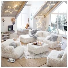 a living room filled with white furniture and lots of lights hanging from the ceiling above