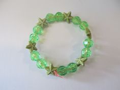 This is a Green Star Beaded Bracelet. It would make a cute gift for a little girl's Birthday. They make cute party favors. It would make a cute addition to a little girl's outfit. It has six green star beads. It has green 8mm faceted beads. It was made with .8mm sturdy stretch string. I tie it several times to prevent breakage. It fits girls ages 4-7. It stretches to fit on the wrist. All items are ready to be shipped I do combined shipping. Items ship in 2-5 business days. Check out more items Playful Green Stretch Bracelet As Gift, Playful Green Beaded Bracelet As A Gift, Cute Green Stretch Bracelet With Round Beads, Cute Green Round Beads Stretch Bracelet, Adjustable Green Charm Bracelet For Party, Beaded Bracelets With Star Charm For Gifts, Star-shaped Beaded Party Bracelets, Green Star-shaped Party Jewelry, Cute Adjustable Star-shaped Bracelets