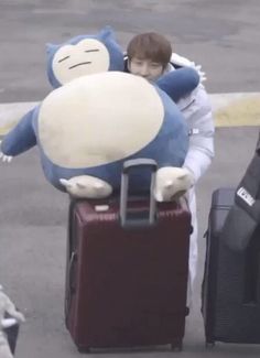 a boy is carrying two suitcases with a stuffed animal on it's back