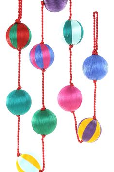 multicolored balls hanging from red string on white background