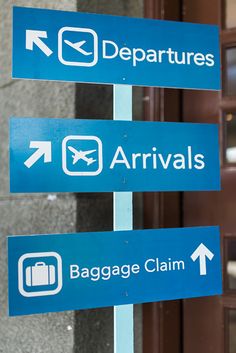 three blue signs pointing in different directions on the side of a building that says departures, baggage claim and departure