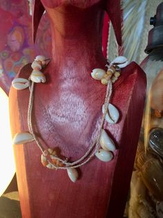 a wooden mannequin with seashells on it's neck and necklace