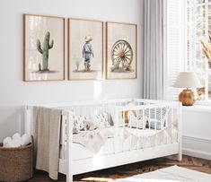 a baby's room with two paintings on the wall and a crib next to it