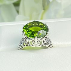 Peridot Sterling Silver RingKing Design#D123 This is a reproduction of a sterling silver Gothic filigree antique ring with a stunning 12 carat green peridot gemstone solitaire. This round cut simulated gem is 15mm in diameter. The inside of the band is marked 925 for sterling silver. Notice the beautiful intricate Gothic claw design of the silver filigree setting. The swirls echo down the band. This large round gemstone sits regally atop the fashionable setting. This stately ring garners attenti Classic Peridot Jewelry For May Birthstone, Classic Silver Ring With Peridot, Classic Silver Peridot Rings, Classic Peridot Jewelry With Accent Stones, Classic Peridot Jewelry With Prong Setting, Elegant Lime Green Jewelry With Center Stone, Classic Peridot Ring Jewelry, Classic Peridot Green Rings, Antique Green Rings With Prong Setting