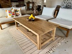 a wooden coffee table sitting on top of a rug next to two white couches