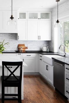 a kitchen with white cabinets and black counter tops is pictured in this image, there are two stools at the center of the island