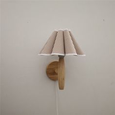 a wooden wall light with a checkered fabric shade on it's arm and wood base