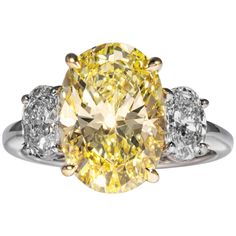 a fancy yellow diamond ring with three diamonds on the band and an oval center stone