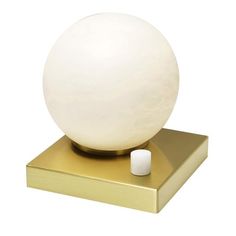 a white ball sitting on top of a gold plated stand with a small candle