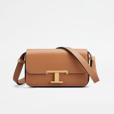 Introducing the T Timeless Crossbody Micro, a unisex bag that seamlessly blends traditional craftsmanship with modern elegance. Designed with a refined calfskin leather and a signature T Timeless buckle, this micro flap bag features a convenient front pocket and an adjustable shoulder strap. Its sleek design is accentuated by saddlery-style stitching and branded metal sliders. Timeless Bags, Gift Boutique, Mini Crossbody, Leather Items, Flap Bag, Leather Mini, Trainers Women, Hobo Bag, Front Pocket