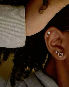 a close up of a person with ear piercings on their ears and behind them is a woman's head