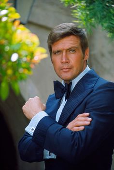 a man in a tuxedo and bow tie posing for the camera with his arms crossed