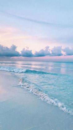 an ocean beach with waves crashing on the shore and clouds in the sky above it