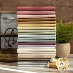 a stack of folded fabric sitting on top of a table next to a potted plant